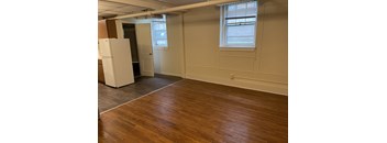 A room with wooden floors and a white refrigerator.