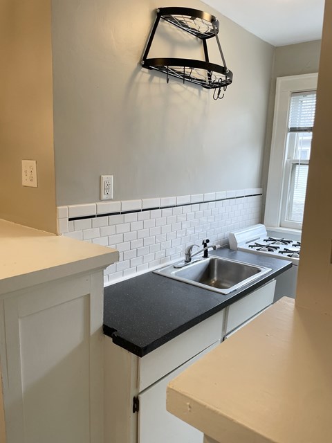 A kitchen with a black countertop and white cabinets.