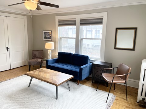 A living room with a blue couch, a brown chair, and a wooden coffee table.