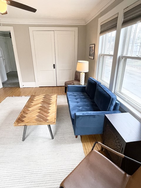 A blue couch sits in a living room with a wooden coffee table.
