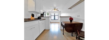 A kitchen with white cabinets and a wooden table.