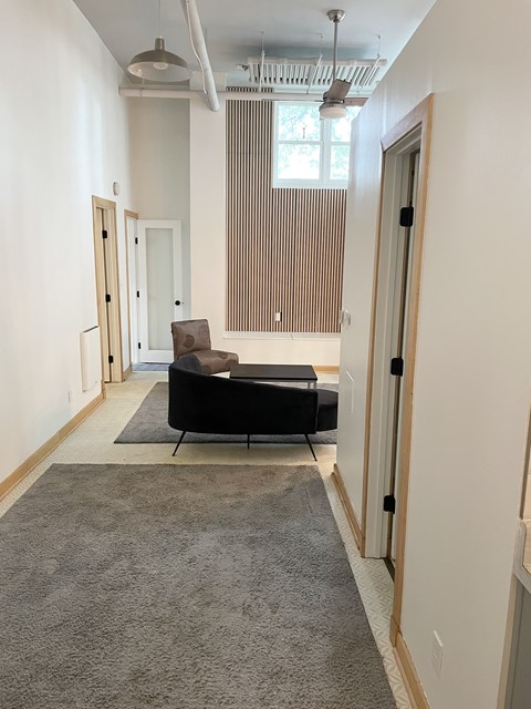 A room with a grey carpet and a black sofa.
