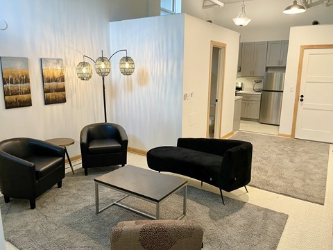 A living room with a black couch, two chairs, and a coffee table.