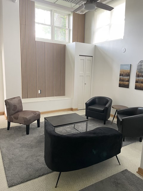 A living room with a black couch and a brown chair.