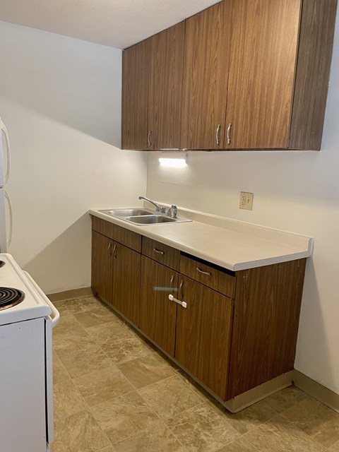 A kitchen with brown cabinets and a white dishwasher.
