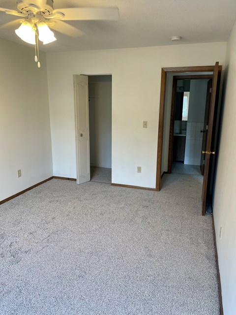 A room with a ceiling fan and carpeted floor.