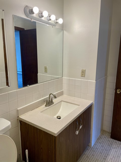 A bathroom with a sink, mirror, and toilet.