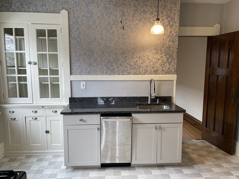 A kitchen with a black counter top and white cabinets.