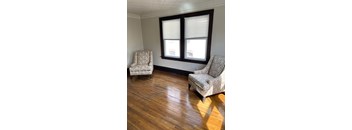 Two chairs are placed in front of a window with wooden flooring.