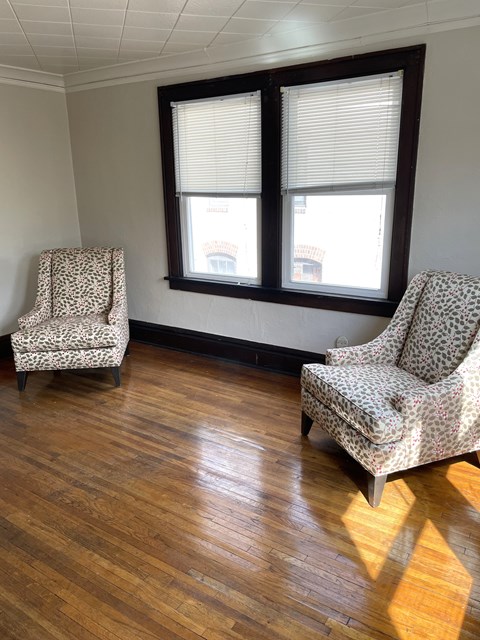 Two chairs are placed in front of a window with wooden flooring.