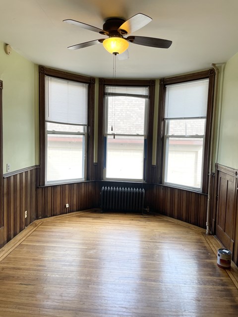 A room with a ceiling fan and wooden floors.