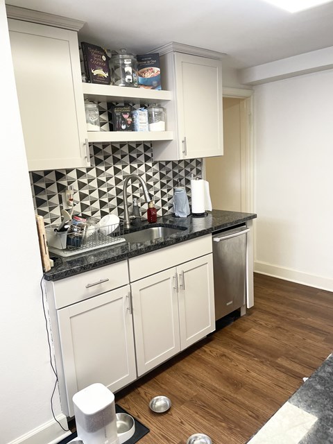 A kitchen with white cabinets and a black counter top.