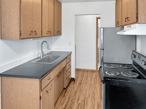 A kitchen with wooden cabinets and a black stove top oven.