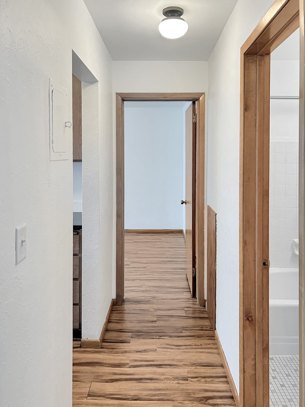 A long hallway with wood floors and white walls.