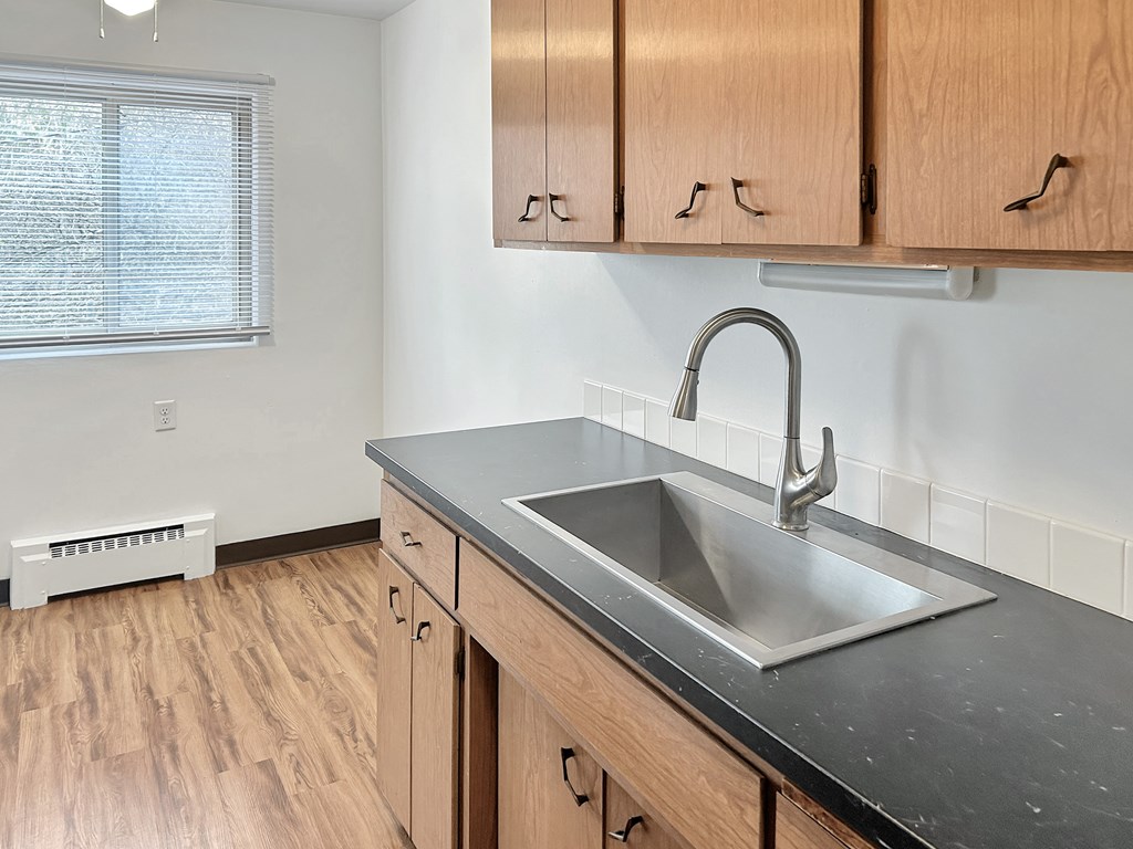 A kitchen with a sink and wooden cabinets.