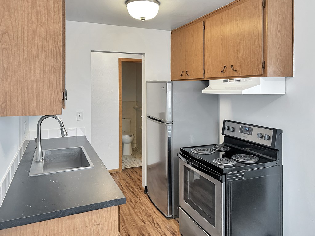 A kitchen with a stove, sink, and cabinets.