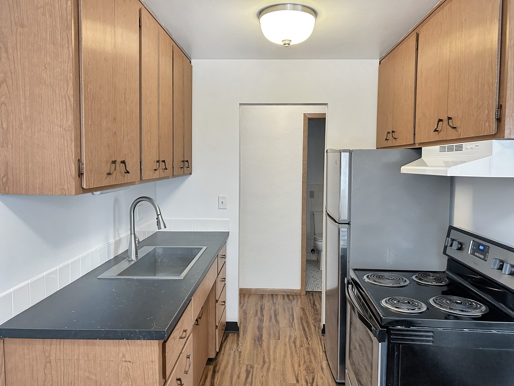 A kitchen with wooden cabinets and a black countertop.