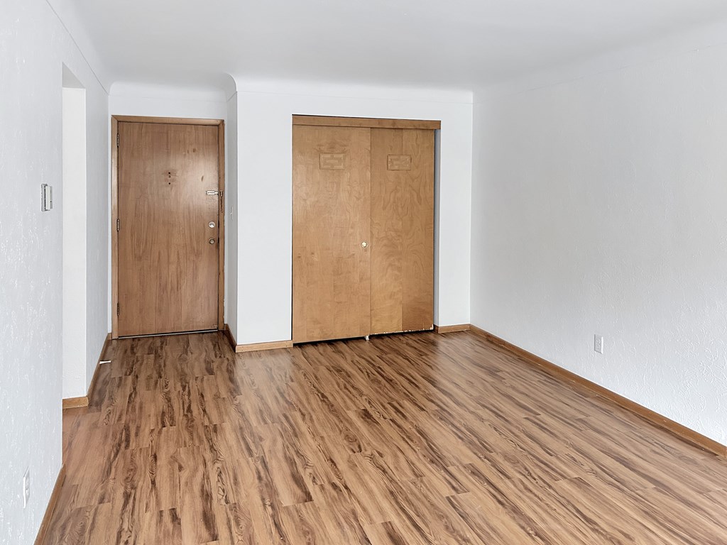 A room with two wooden doors and wooden flooring.