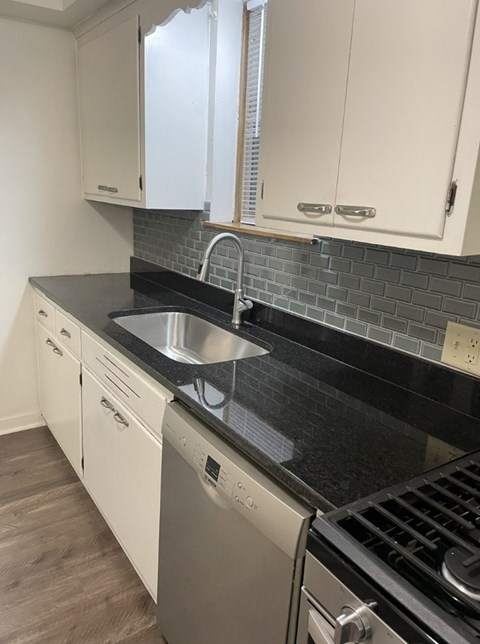 A kitchen with a black countertop and white cabinets.