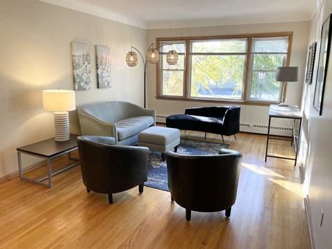 A living room with a grey couch, a black chair and a black ottoman.