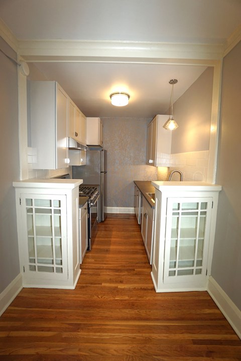 A kitchen with white cabinets and a wooden floor.