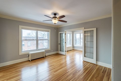 A room with a ceiling fan and wooden floors.