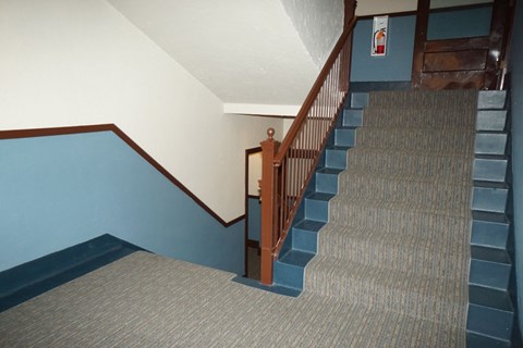 A staircase with a carpeted floor and wooden handrail.