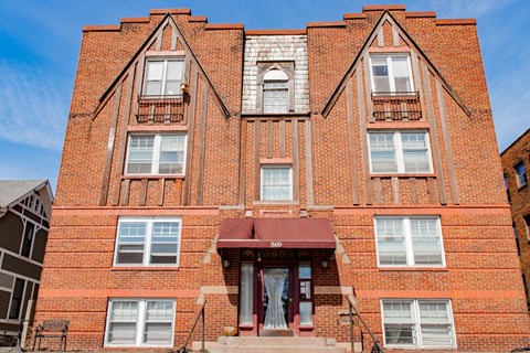 A red brick building with a balcony and a door.