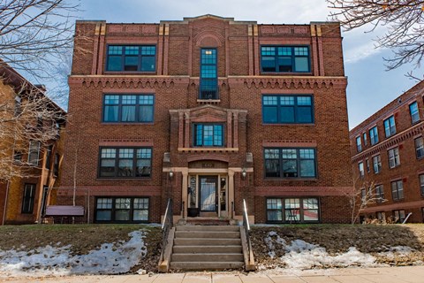 A red brick building with a staircase leading to the entrance.