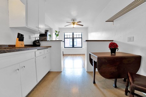A kitchen with white cabinets and a wooden table.