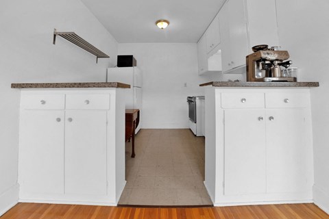 A kitchen with white cabinets and a wooden floor.