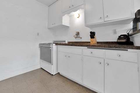 A kitchen with white cabinets and a wooden knife block.