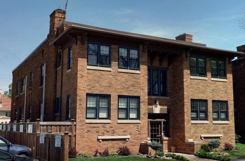 A red brick house with a car parked in front.