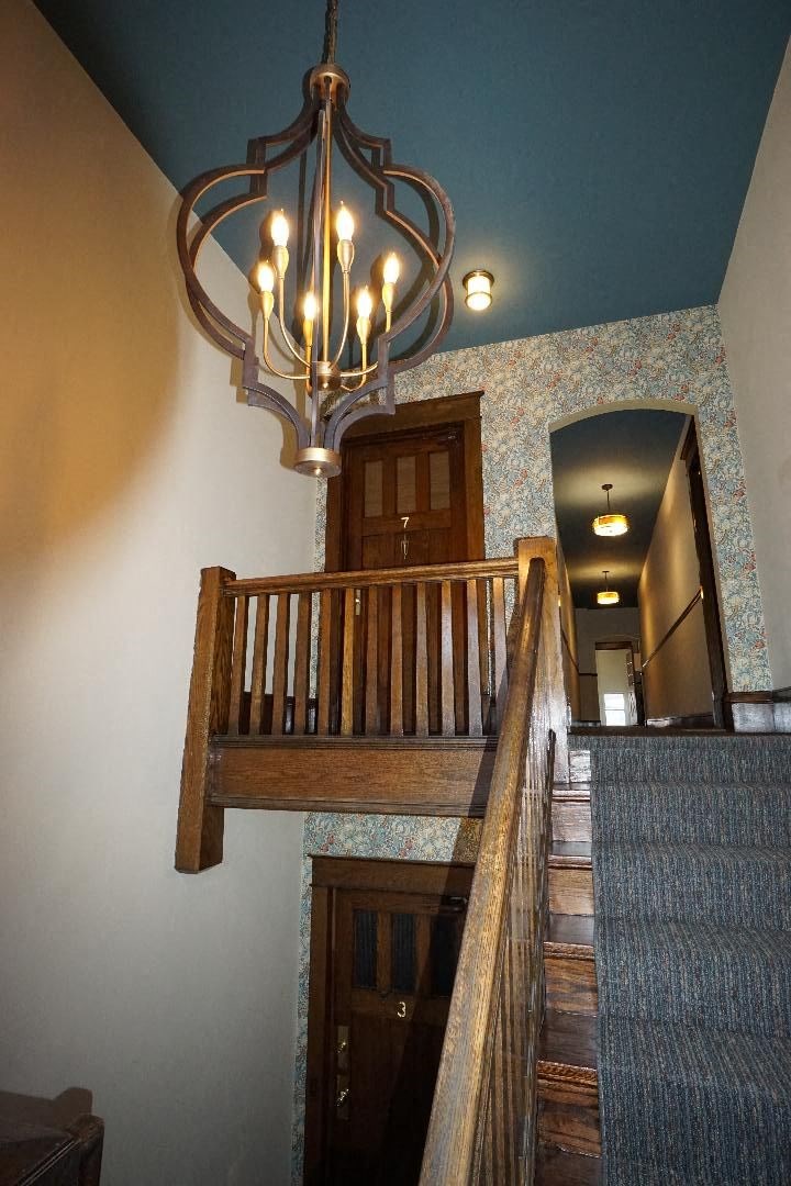 A staircase with a chandelier hanging above it.
