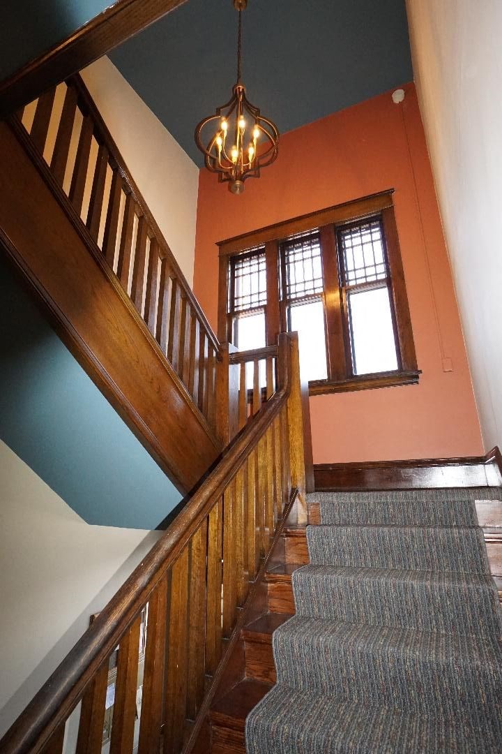 A staircase with a wooden banister and a chandelier hanging from the ceiling.