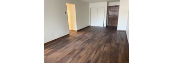 A room with wooden floors and a white wall with a door and a window.
