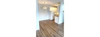A kitchen with a white refrigerator and wooden floors.