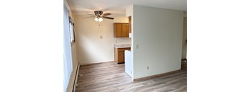 A room with a ceiling fan and wooden cabinets.