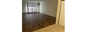 A room with wooden flooring and a window with blinds.