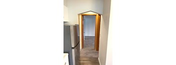 A kitchen with a refrigerator and a doorway leading to another room.