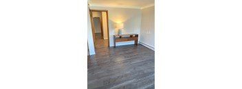 A room with a wooden floor and a bench with a lamp on it.