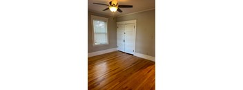 A room with a ceiling fan and a wooden floor.