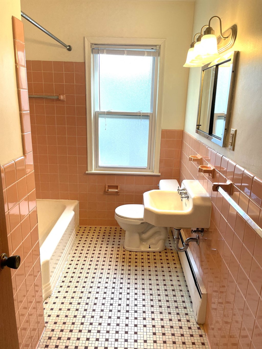A bathroom with a toilet, sink, and window.