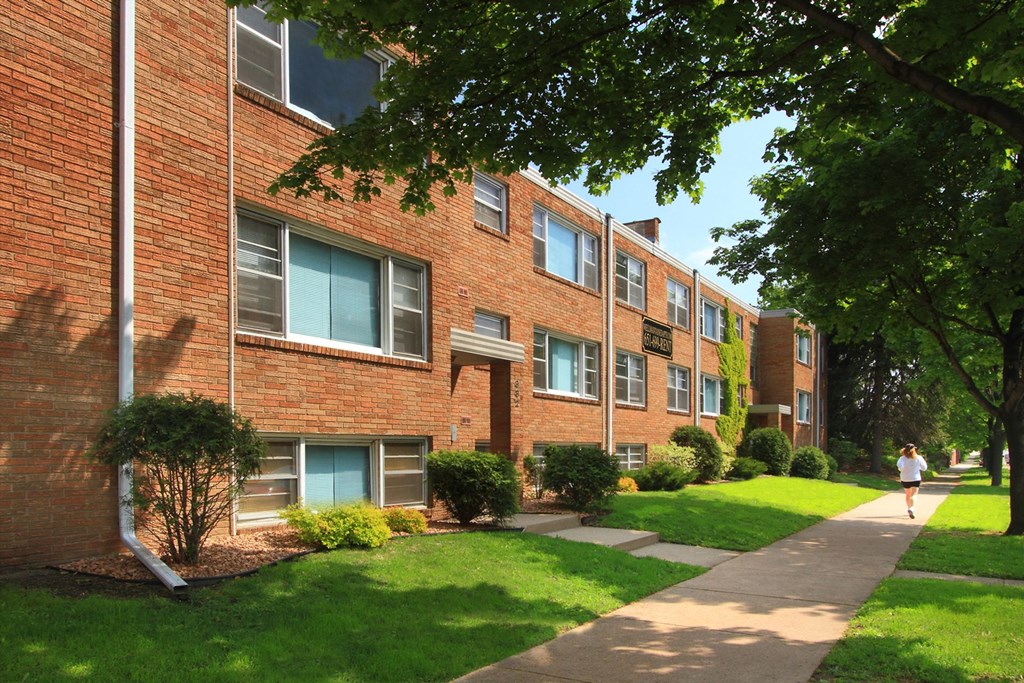 A person is walking on a path in front of a brick building.