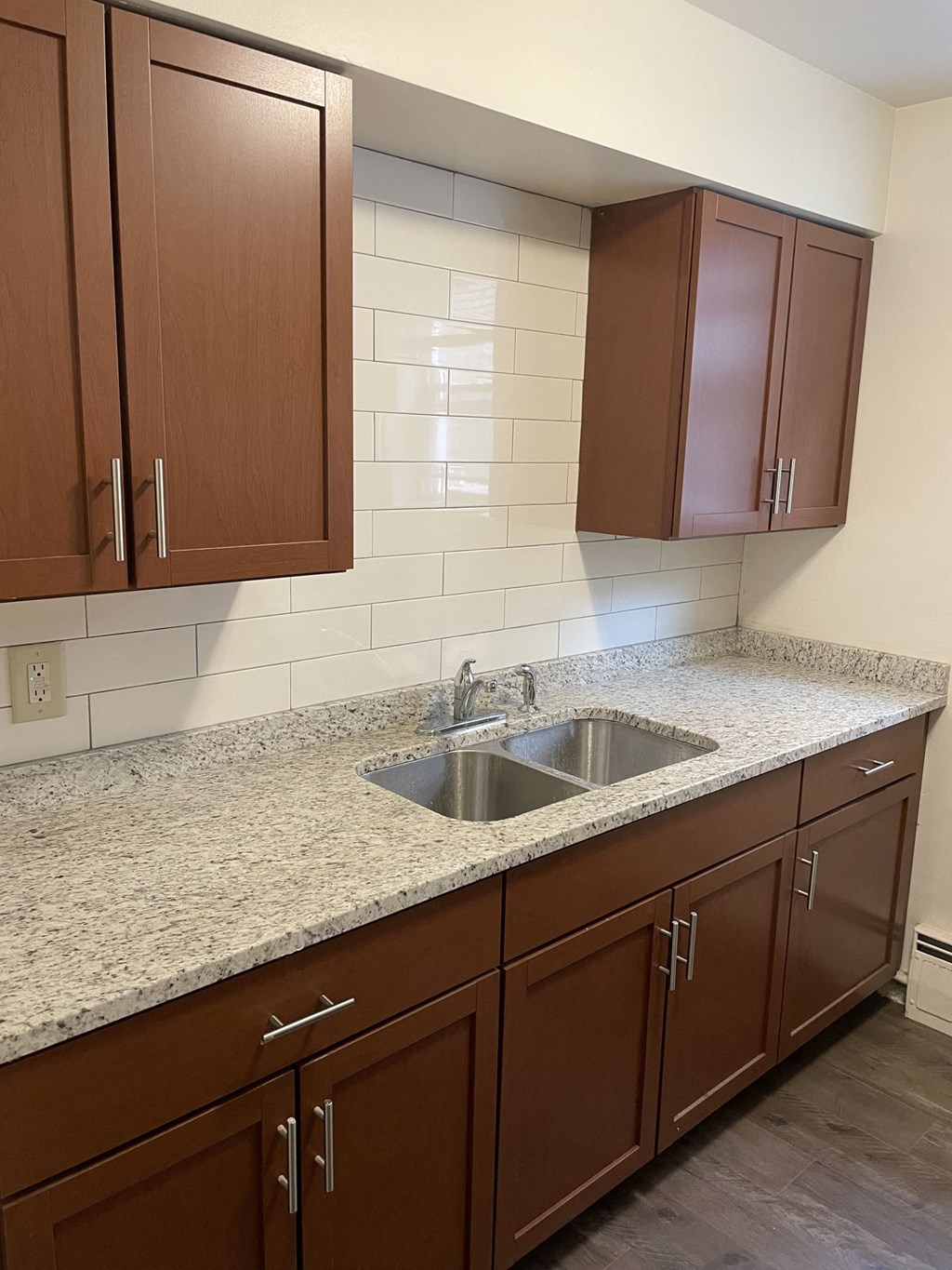 Brown cabinets with silver handles and a sink in between.