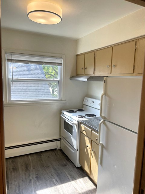 A small kitchen with a white fridge, stove and dishwasher.