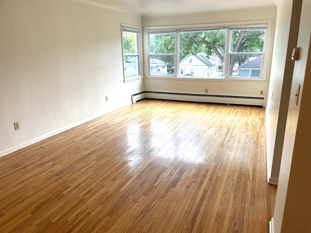 A room with wooden flooring and a large window.
