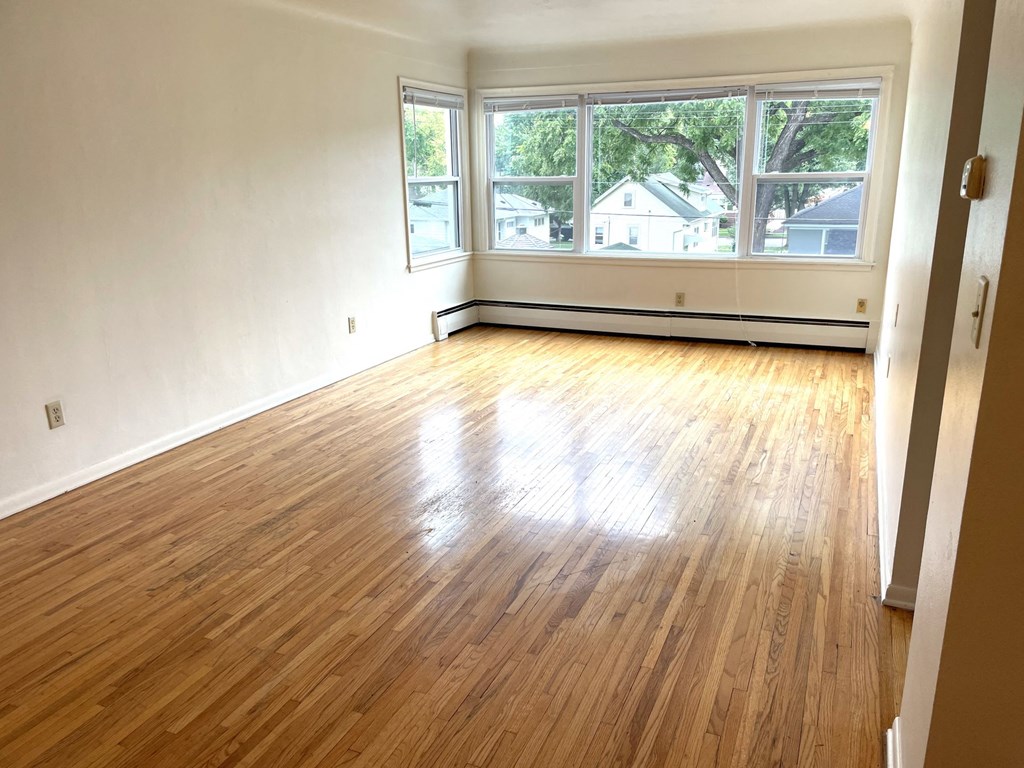 A room with wooden flooring and a large window.