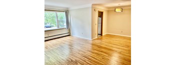 A room with wooden flooring and a window overlooking a street.