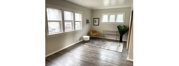 A room with a chair, a plant, and a picture frame on the wall.